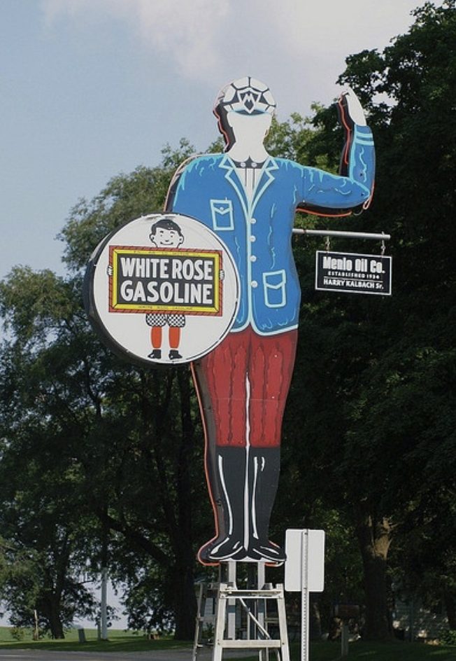Kalbach Oil friendly gas station man statue in Menlo, Iowa, waving beside the White Rose Gasoline sign