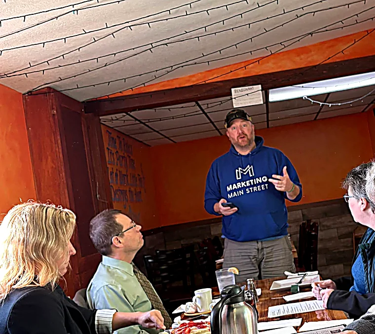 Nate Westre speaking to a Toastmasters group in a Marketing Main Street hoodie