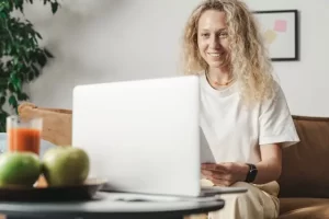 Woman smiling at a laptop, displaying the importance of leaving a good first impression on users.