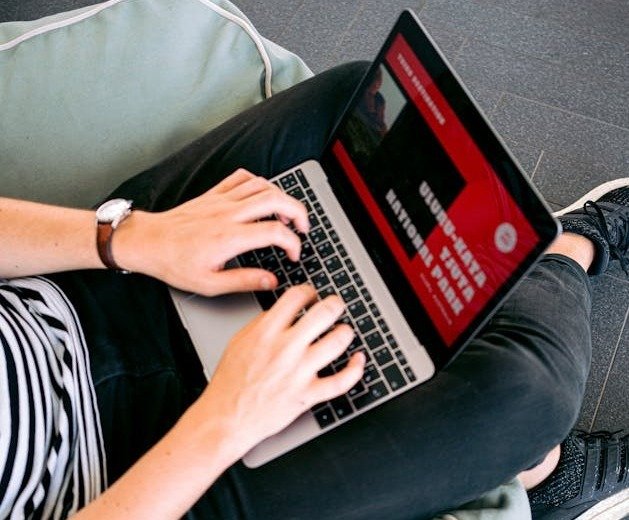 Person working on a laptop to update a website, emphasizing the importance of regular website updates for redesigns.
